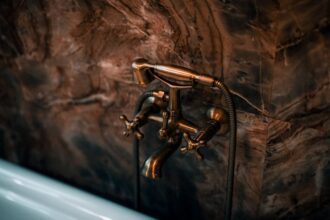 dornbracht - Elegant brass faucet fixture with a luxurious marble wall background.