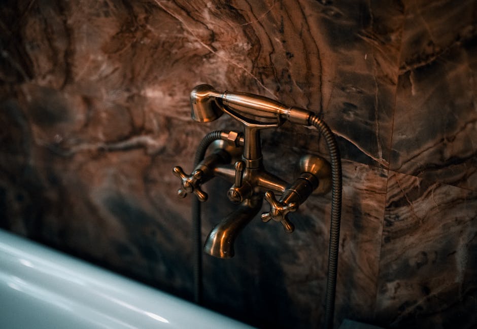 dornbracht - Elegant brass faucet fixture with a luxurious marble wall background.