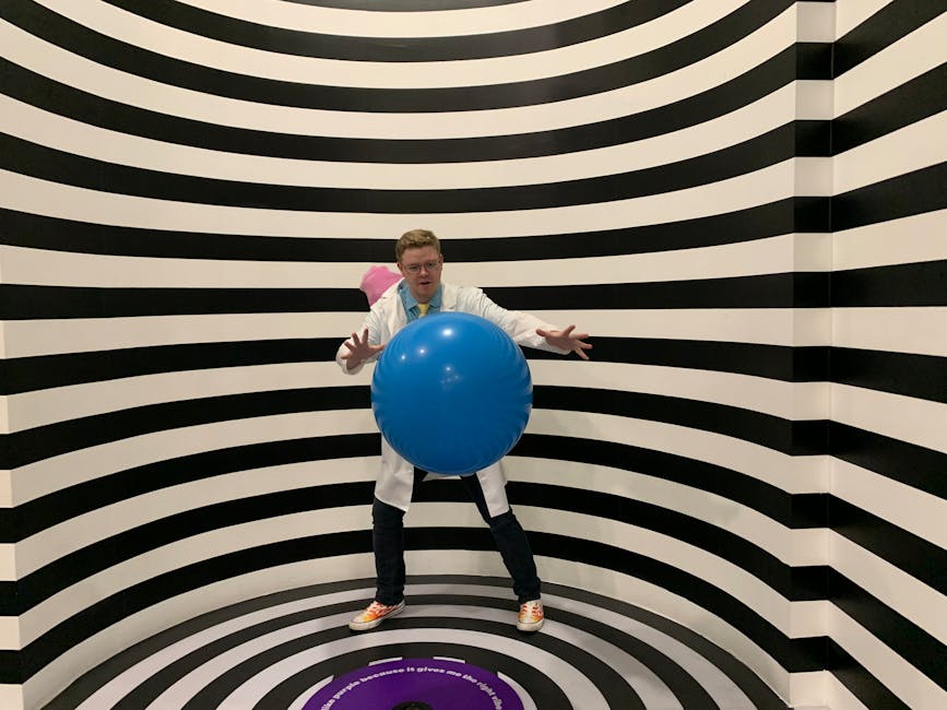 illuseum berlin - A man wearing a lab coat poses with a blue ball in a striped illusion room.