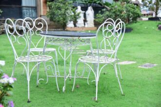 siena garden - White iron table and chairs set on a vibrant green lawn outdoors.