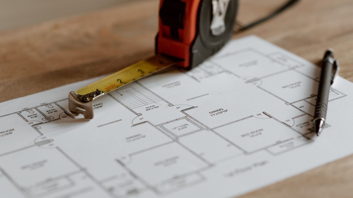 Renovierungsunterlagen mit Kostenvoranschlag, Zollstock und Werkzeug auf einem Tisch